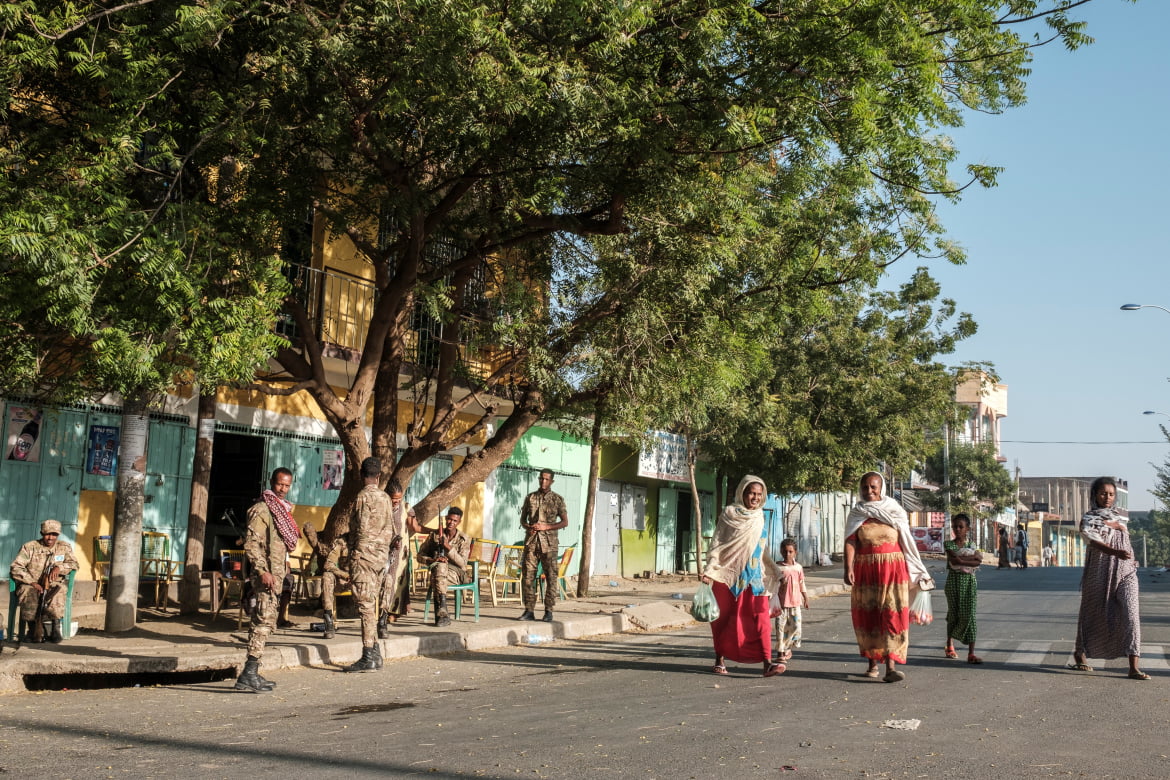 A group of women and children walk next to members of the Amhara Special Forces in a Humera street. [Eduardo Soteras/AFP]