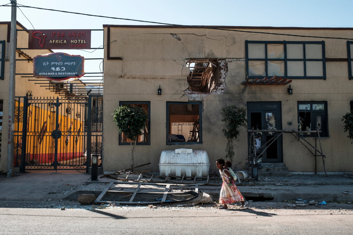 Children play in front of a hotel damaged by mortar shelling. [Eduardo Soteras/AFP]
